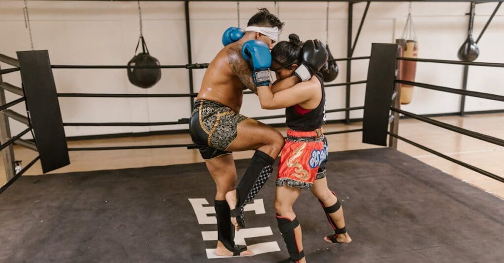 Two fighters clinch with knees during Muay Thai basics practice