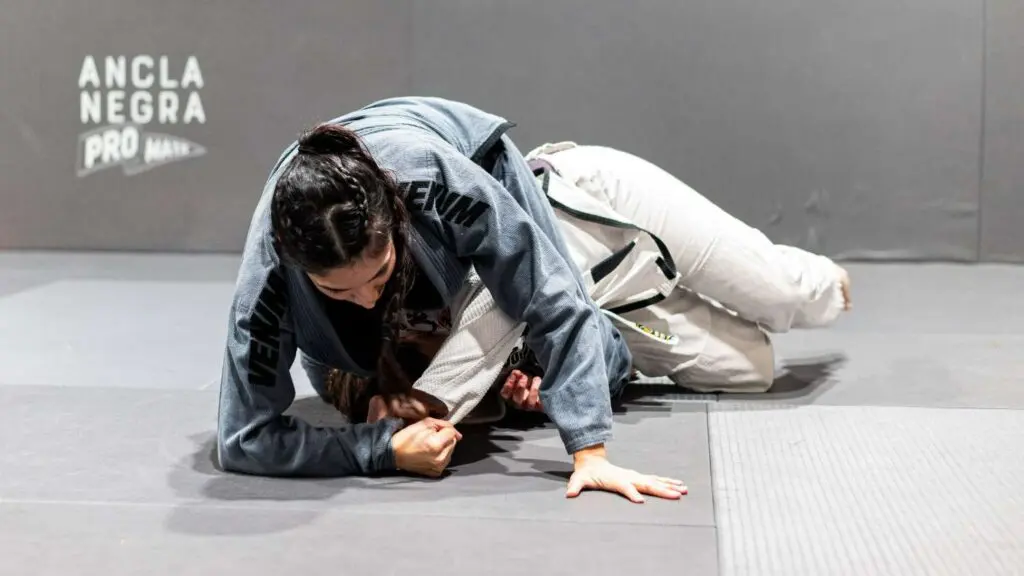 A female grappler securing side control over her opponent on the mat during a training session, demonstrating adult Brazilian Jiu Jitsu positional hierarchy.
